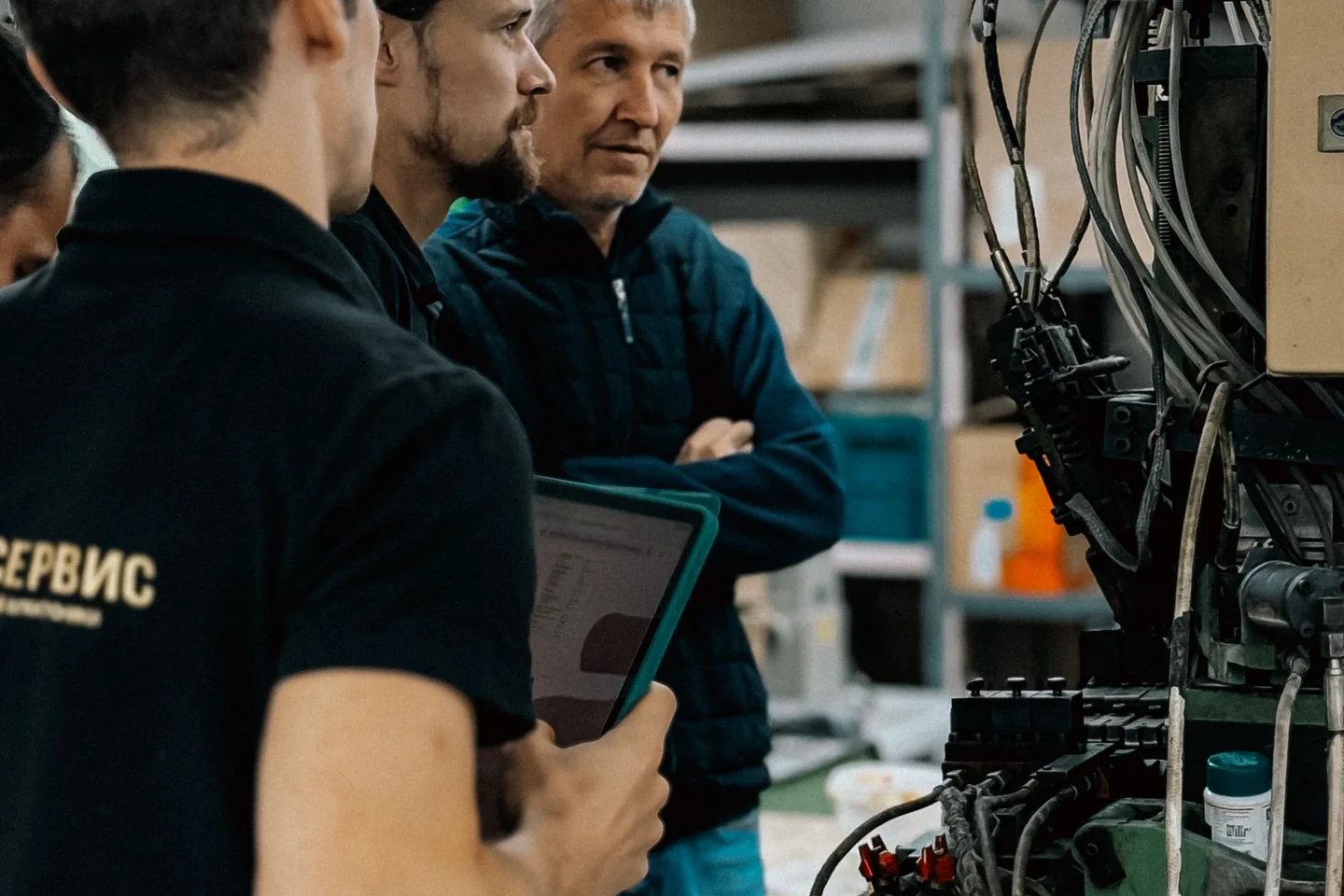 Mitarbeiter besprechen gemeinsam einen Arbeitsablauf direkt an einer Produktionsmaschine