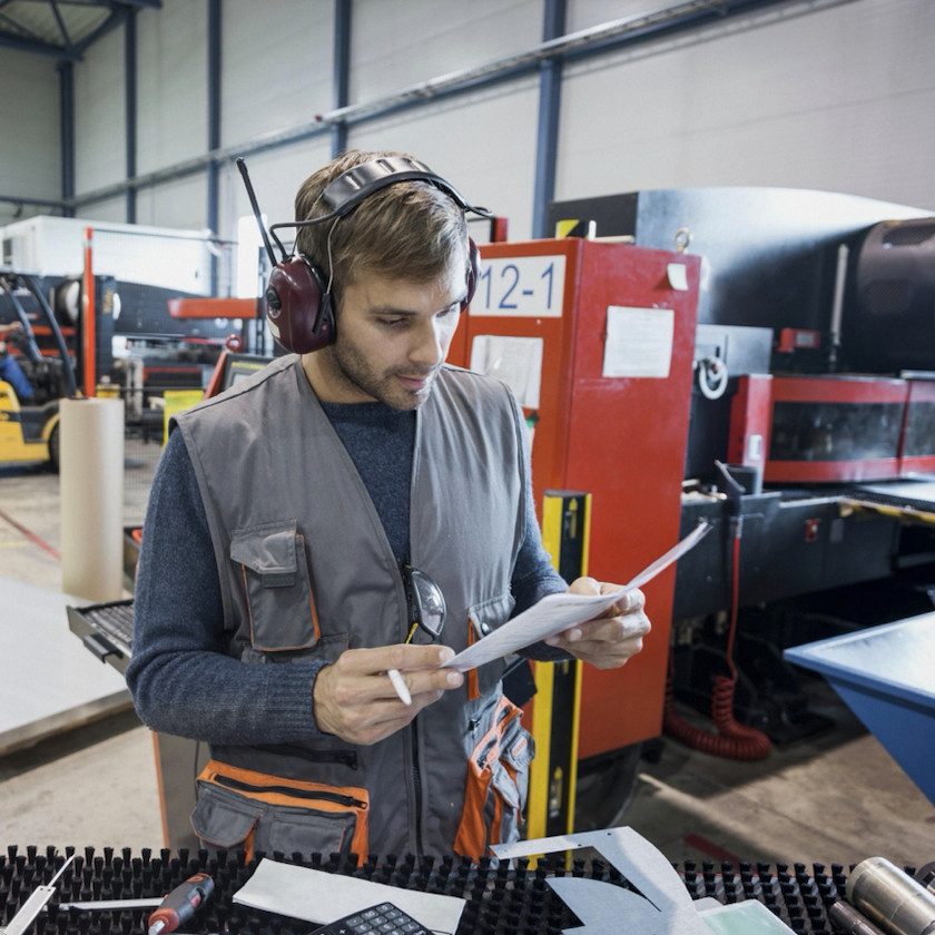 Mitarbeiter prüft Arbeitsunterlagen direkt im Produktionsbereich